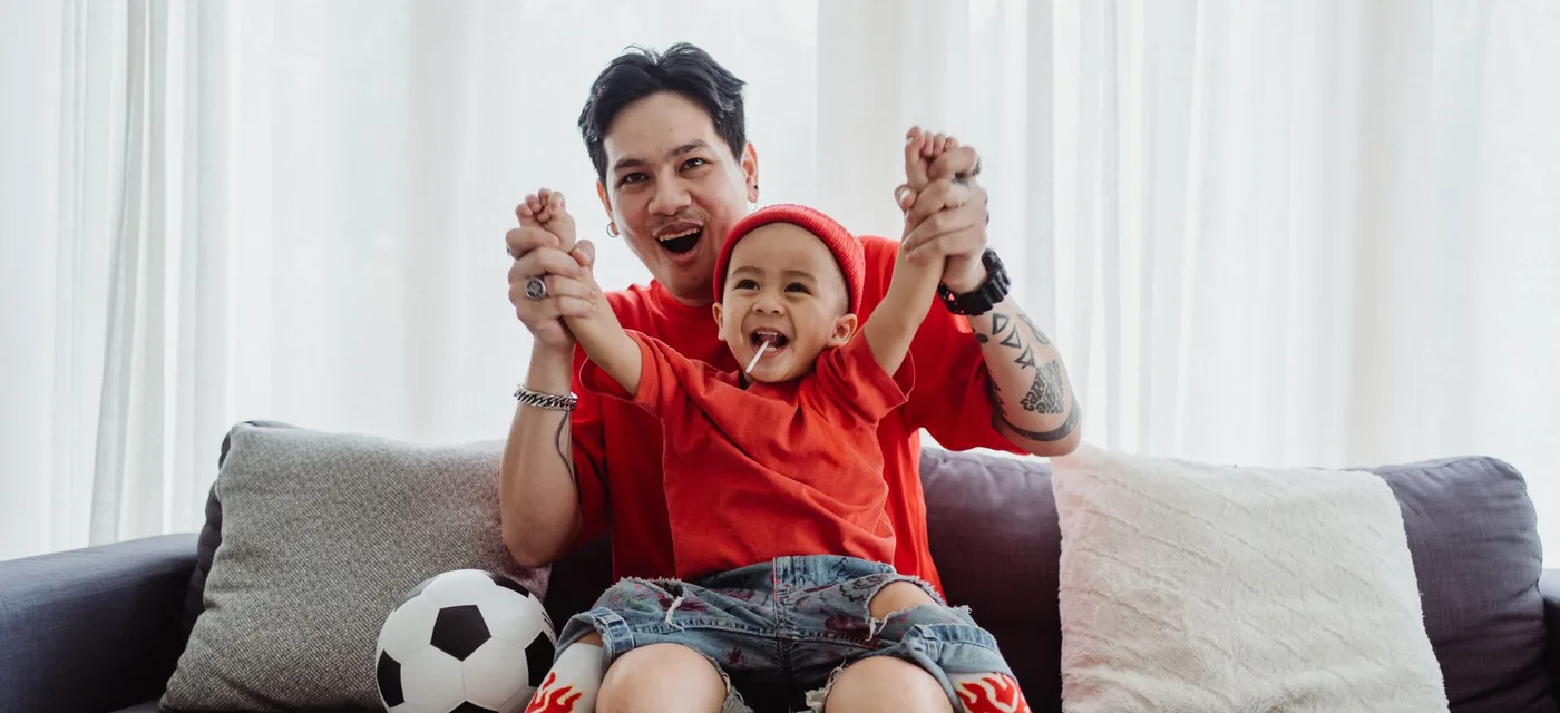 Pai e filho comemorando um gol no sofá durante o teste IPTV grátis